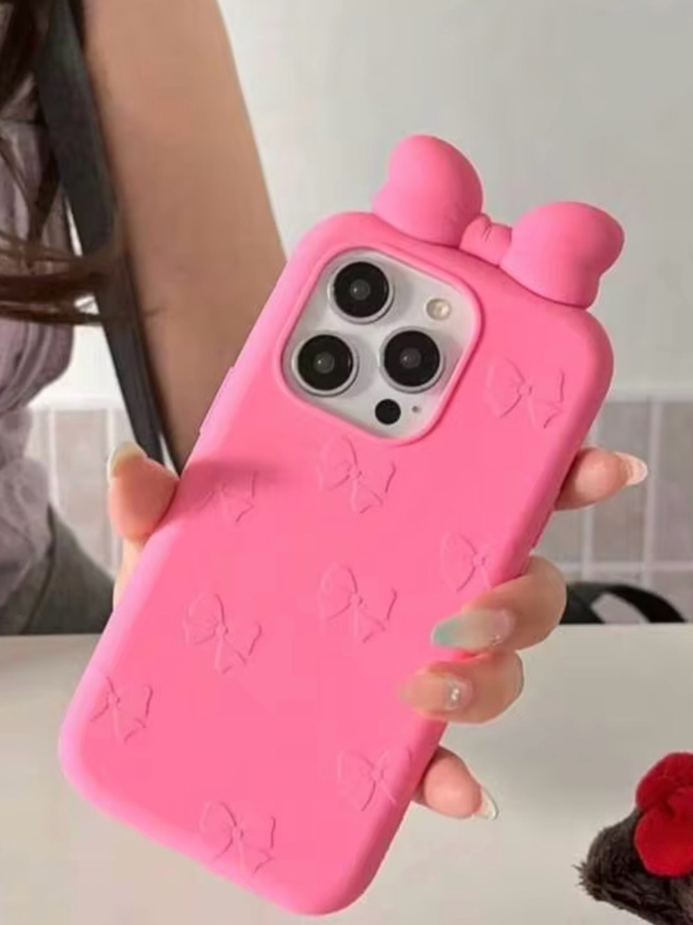 Soft pink silicone phone case with raised bow accents.